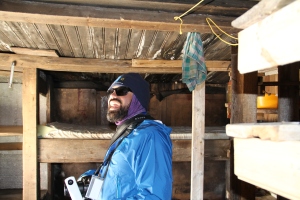 Enrique in the trapper's cabin. Bunk beds, dart board, short ceilings.