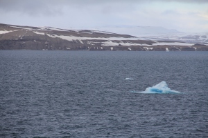 A small blue iceberg drifts past the ship.